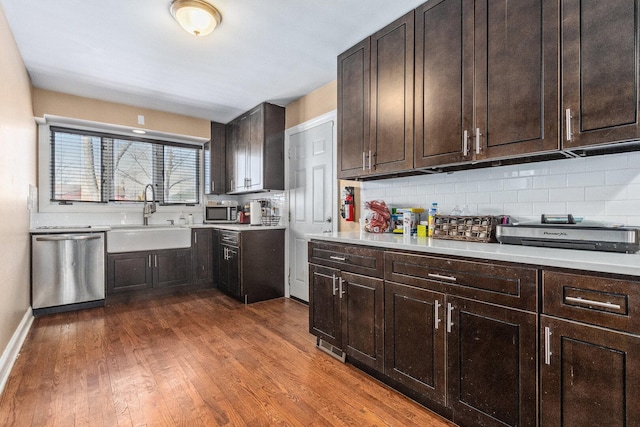 kitchen with appliances with stainless steel finishes, dark wood-type flooring, a sink, and decorative backsplash