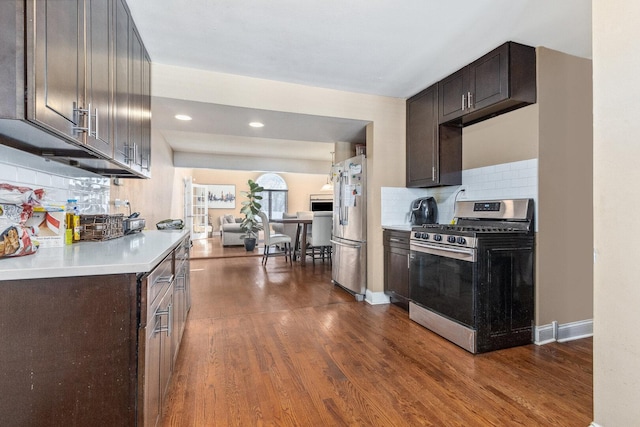 kitchen with stainless steel appliances, light countertops, backsplash, dark wood-type flooring, and dark brown cabinets