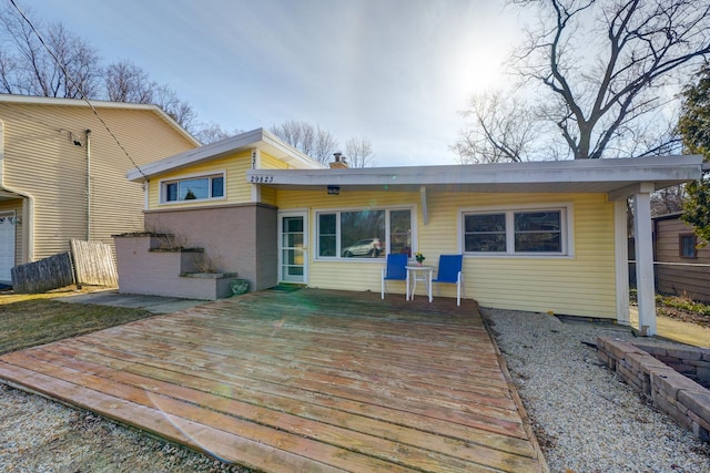 back of property with brick siding, fence, a chimney, and a wooden deck