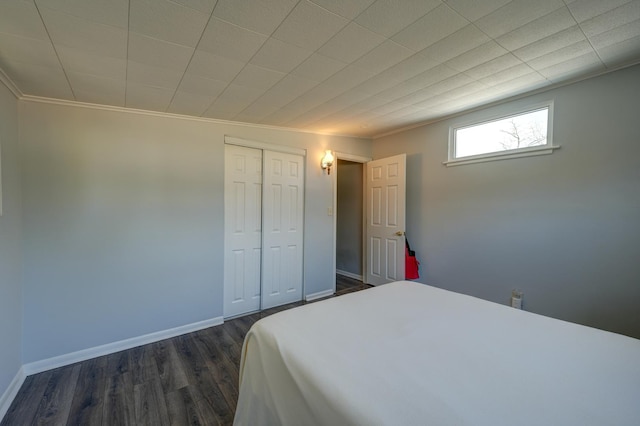 bedroom featuring crown molding, dark wood-type flooring, a closet, and baseboards