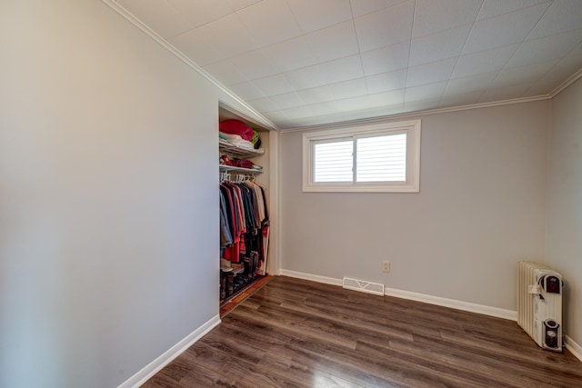 interior space with visible vents, baseboards, radiator, dark wood-style floors, and crown molding