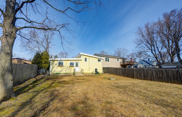 rear view of house with a fenced backyard and a lawn