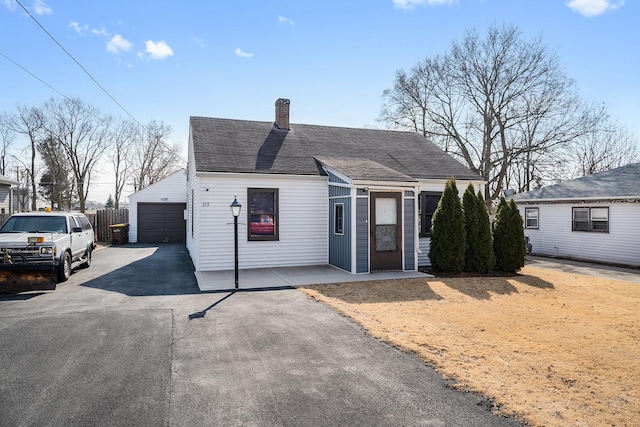 view of front of property with a garage, an outdoor structure, driveway, roof with shingles, and a chimney