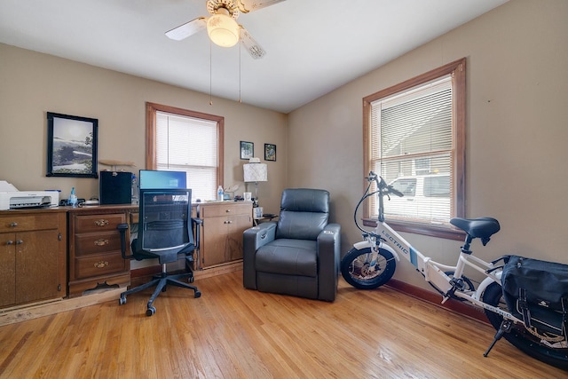 office area with light wood finished floors, a wealth of natural light, and a ceiling fan