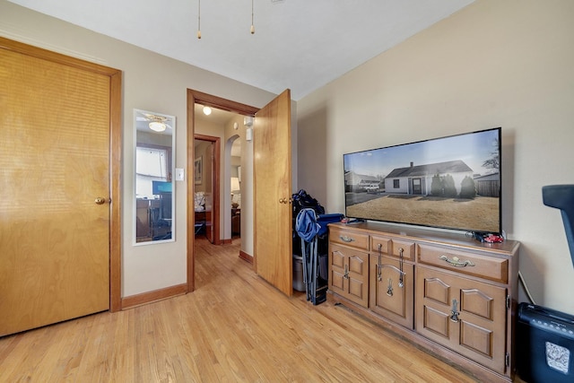 hallway featuring light wood-style flooring, arched walkways, and baseboards