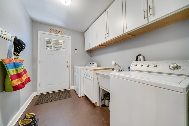 laundry area featuring washer and dryer, cabinet space, and baseboards