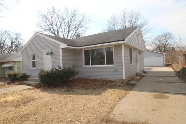 view of front of property featuring a garage, roof with shingles, and an outbuilding