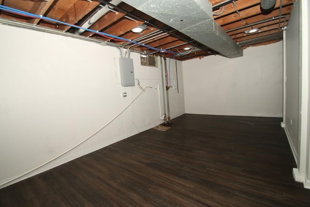 unfinished basement featuring electric panel and wood finished floors