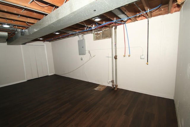 unfinished below grade area featuring electric panel and wood finished floors