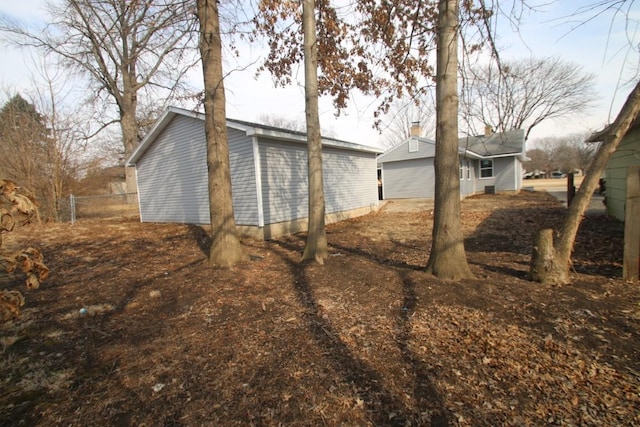 view of property exterior with a garage, fence, and an outbuilding