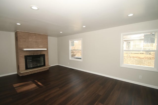 unfurnished living room with dark wood-type flooring, a fireplace, recessed lighting, and baseboards