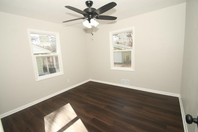 spare room with dark wood-style floors, visible vents, baseboards, and ceiling fan