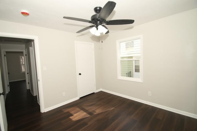 unfurnished bedroom featuring a ceiling fan, baseboards, dark wood finished floors, and a closet