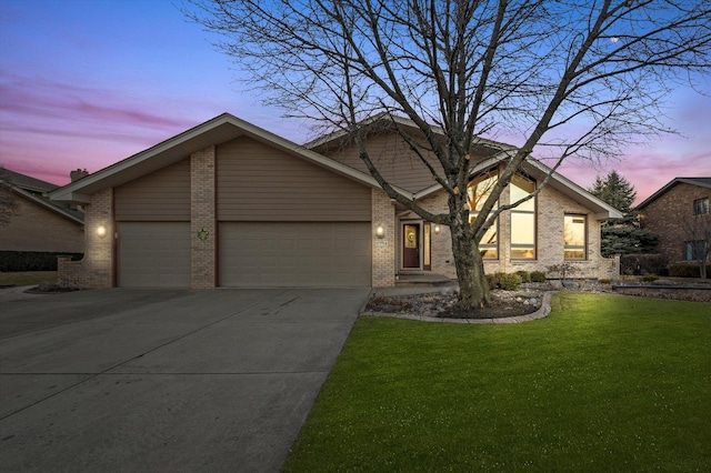 view of front of home with a garage, a yard, driveway, and brick siding