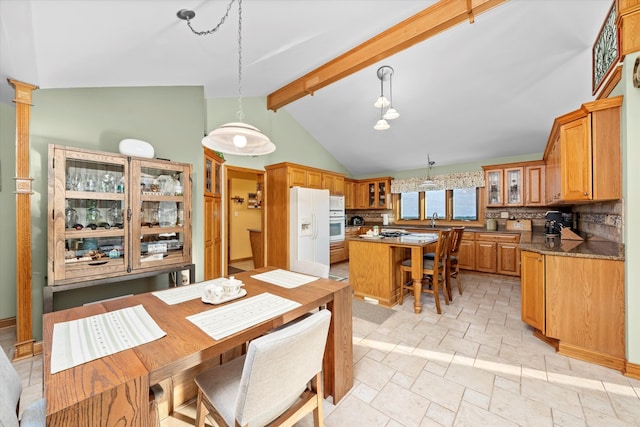 dining area featuring lofted ceiling with beams and stone finish floor