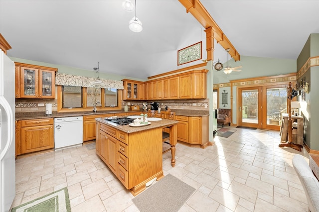 kitchen with decorative backsplash, white appliances, a sink, and stone tile floors