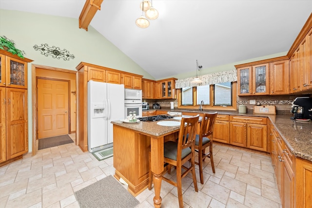 kitchen with white appliances, stone finish flooring, decorative backsplash, and a center island