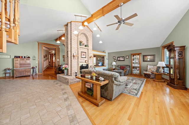 living room featuring a fireplace, wood finished floors, a ceiling fan, stairs, and beamed ceiling