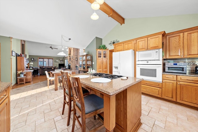 kitchen featuring white appliances, open floor plan, beamed ceiling, light stone countertops, and stone tile flooring