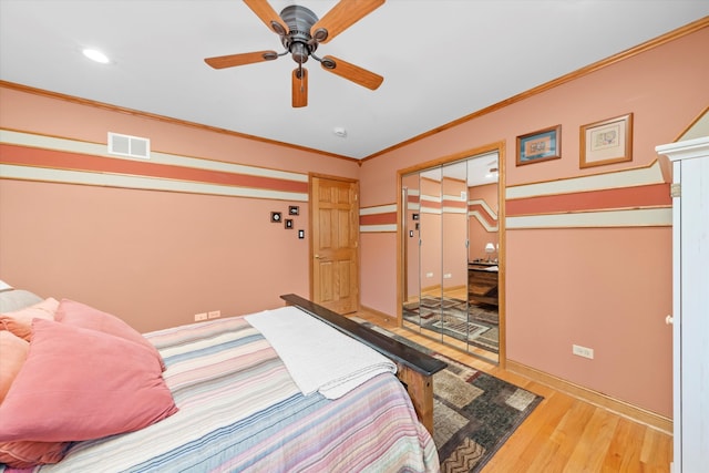 bedroom with visible vents, a ceiling fan, wood finished floors, crown molding, and a closet