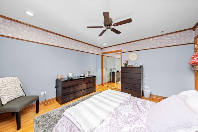 bedroom with wood finished floors, crown molding, and wallpapered walls