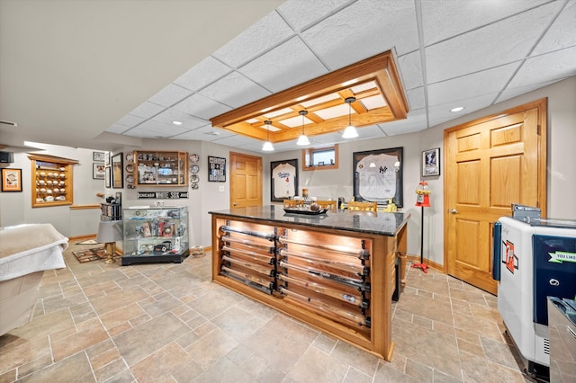 kitchen with stone finish floor, baseboards, dark stone countertops, and a center island