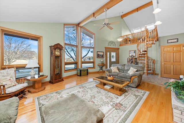 living area featuring wood finished floors, beamed ceiling, and stairs