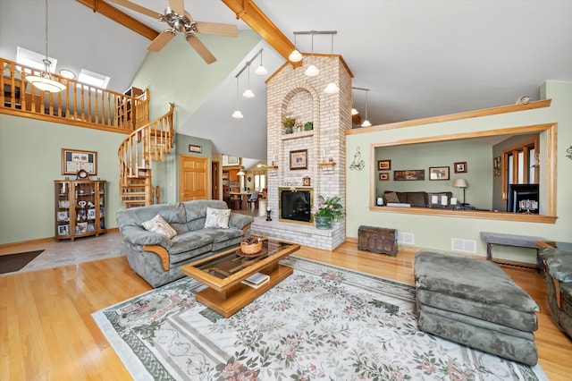 living room featuring stairway, a fireplace, visible vents, and wood finished floors