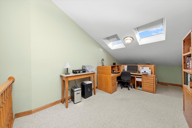 office area featuring baseboards, vaulted ceiling with skylight, and light colored carpet