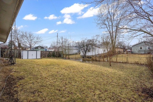 view of yard featuring a storage shed, a fenced backyard, and an outdoor structure