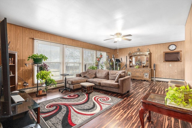 living room featuring ceiling fan, wooden walls, baseboard heating, and wood finished floors