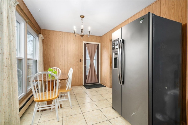 kitchen with light tile patterned floors, stainless steel fridge, wooden walls, an inviting chandelier, and baseboard heating