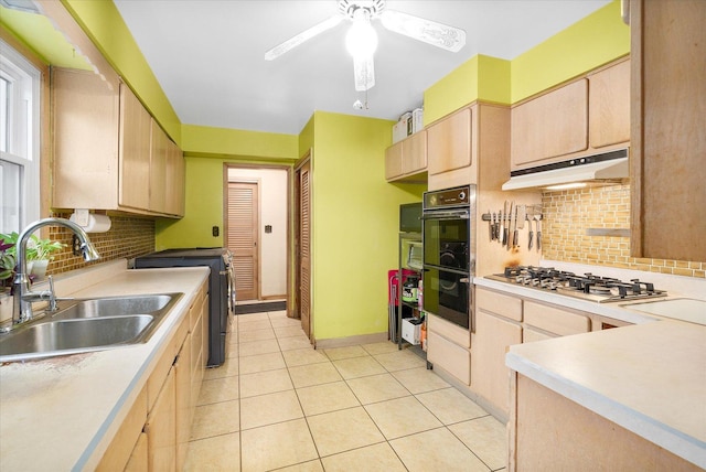 kitchen featuring under cabinet range hood, a sink, light countertops, light brown cabinetry, and stainless steel gas stovetop