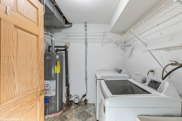 laundry room with washing machine and dryer, laundry area, water heater, and stone finish flooring