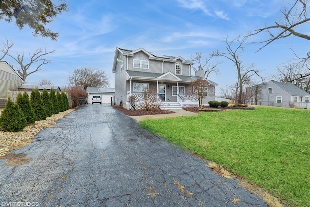 view of front of property with driveway, covered porch, fence, and a front yard