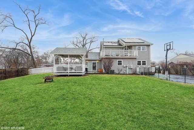 back of property with a deck, a fenced backyard, a lawn, and a balcony