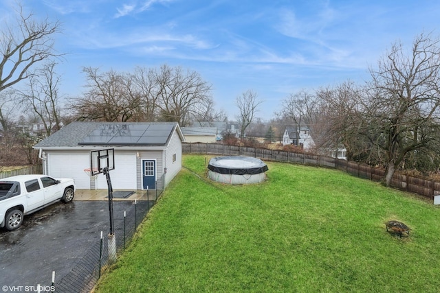 view of yard with a garage, an outbuilding, fence, and a fenced in pool