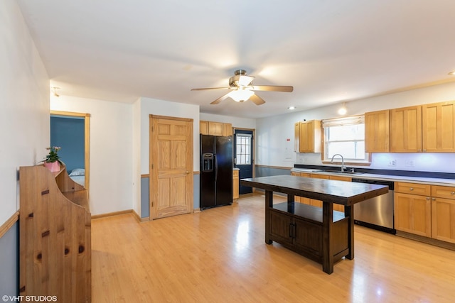 kitchen featuring a sink, black fridge, light wood-style floors, and dishwasher