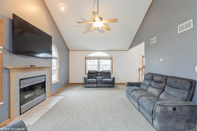 living area with high vaulted ceiling, a fireplace, visible vents, and light colored carpet