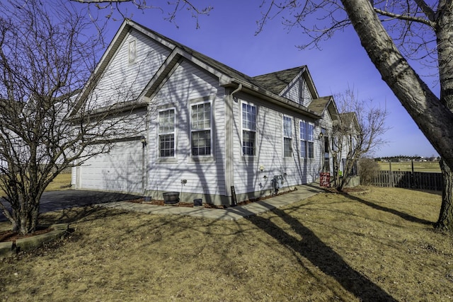 view of home's exterior featuring aphalt driveway, a lawn, and fence