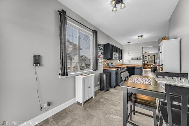 kitchen with stainless steel appliances, hanging light fixtures, and baseboards