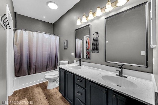 bathroom featuring double vanity, a sink, toilet, and wood finished floors