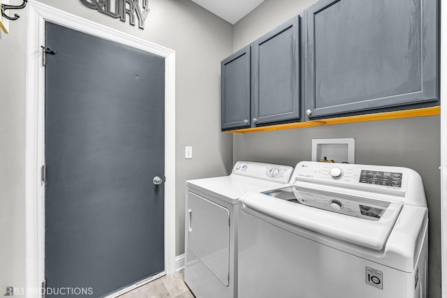 laundry area featuring washer and clothes dryer, cabinet space, and baseboards