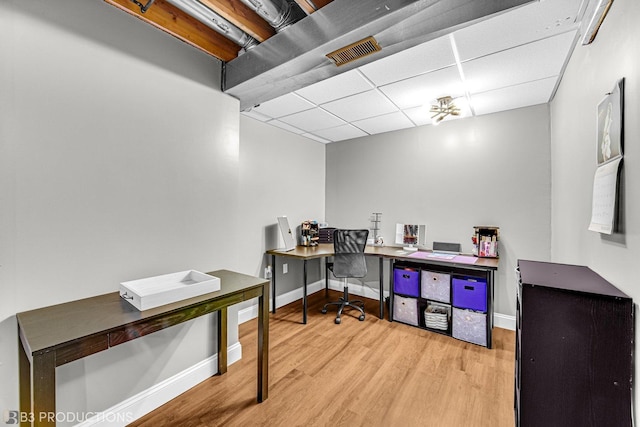 office area with a paneled ceiling, visible vents, baseboards, and wood finished floors