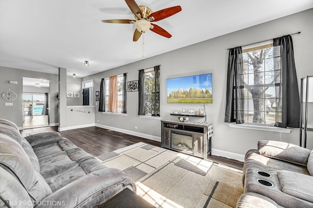 living room featuring a wealth of natural light, a ceiling fan, baseboards, and wood finished floors