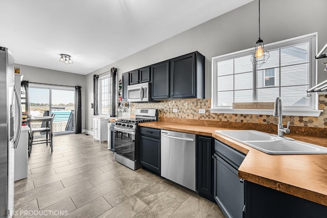 kitchen with appliances with stainless steel finishes, decorative light fixtures, a sink, and backsplash