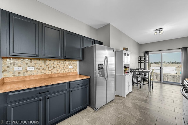 kitchen with light countertops, backsplash, and stainless steel fridge with ice dispenser