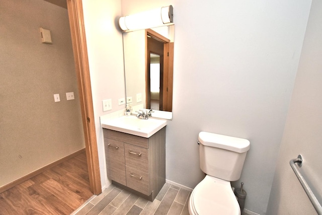 bathroom featuring vanity, wood finished floors, toilet, and baseboards