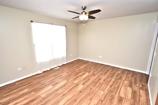 spare room with ceiling fan, light wood finished floors, visible vents, and baseboards