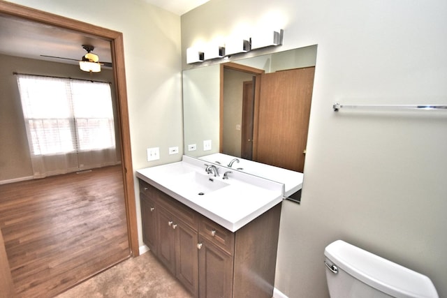 half bathroom featuring toilet, ceiling fan, baseboards, and vanity